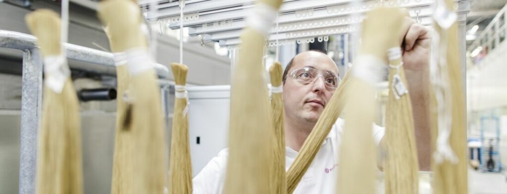 Evonik employee in Austria hangs bundled SEPURAN membrane fibers on a frame. The fibers are used for gas treatment.