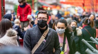 People wearing face masks, walking along busy thoroughfare