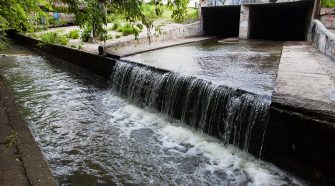 Stormwater stream flowing out underground tunnel into river.